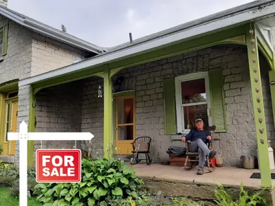 Limestone house with a for sale sign