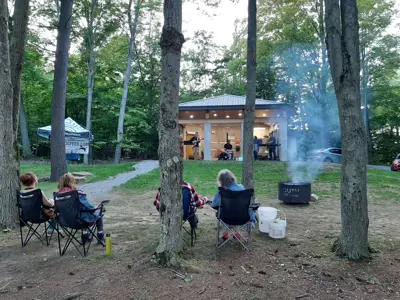 People sitting in lawn chairs facing a band playing music outside.