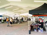 Event tents and people walking around a vendor market under a large outdoor pavillion